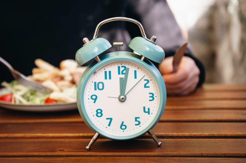 closeup-alarm-clock-blurred-food-background